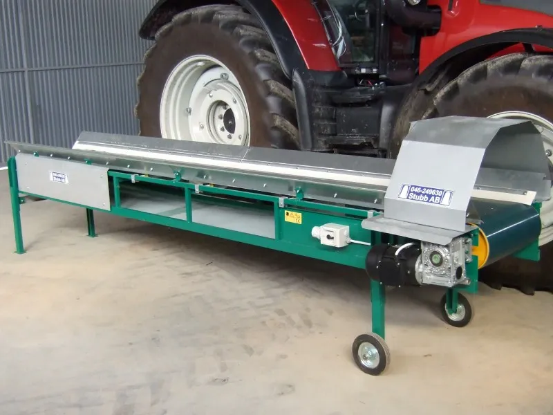 Grönt transportband med Stubb AB-skylt framför en traktor